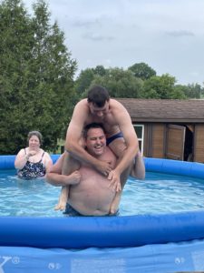 Me on my knees in a pool while my brother tries to climb his large self onto my shoulders.